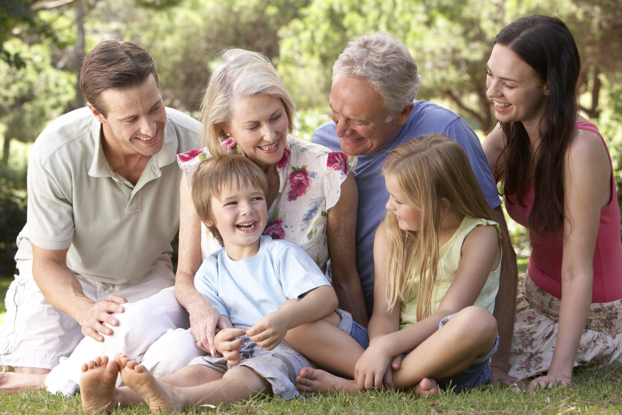 Three Generation Family Sitting In Park Together